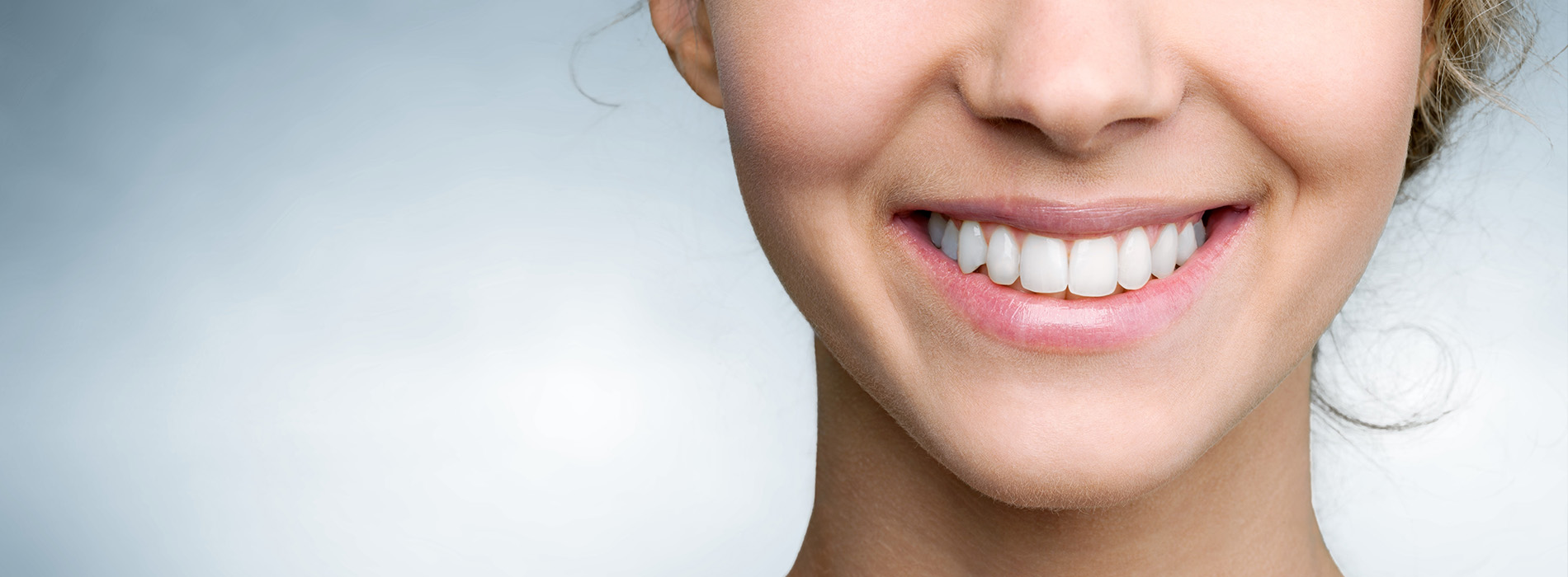 A smiling woman with fair skin against a blurred background.