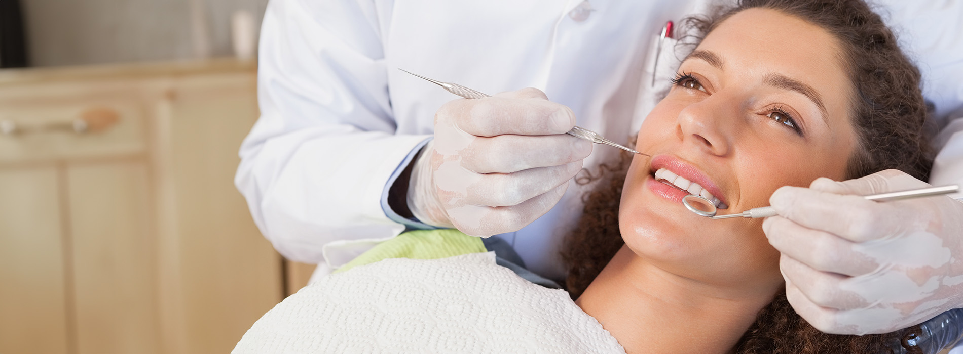 A dentist performing dental work on a patient s teeth while wearing gloves and a face mask.