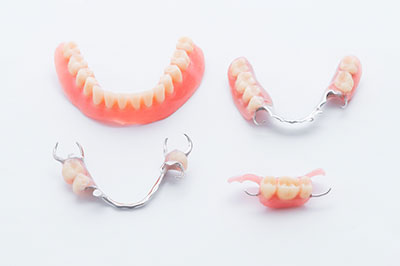 The image displays a collection of dentures with visible teeth, including upper and lower sets, presented on a white background.