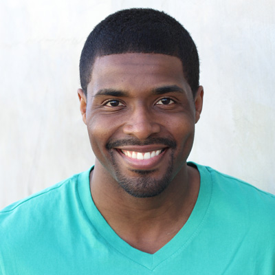 An elderly couple sharing a warm embrace, smiling at the camera against a scenic backdrop.