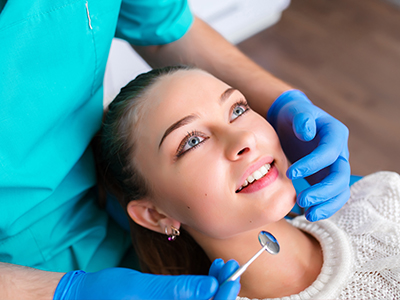 A dental hygienist performing a teeth cleaning procedure on a patient s mouth.